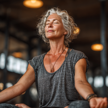 Idősebb hölgy meditál békésen a jóga óra alatt